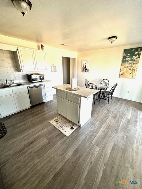 kitchen featuring white cabinetry, stainless steel dishwasher, sink, and a center island