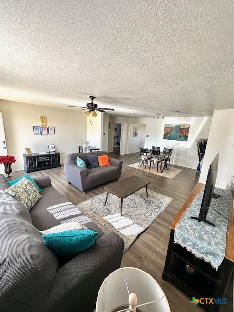 living room with hardwood / wood-style floors, ceiling fan, and a textured ceiling