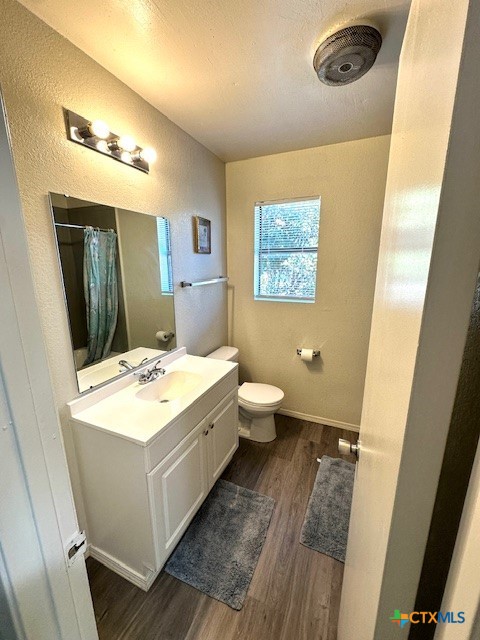 bathroom featuring wood-type flooring, toilet, a textured ceiling, vanity, and a shower with shower curtain