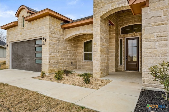 doorway to property with stone siding, driveway, and an attached garage