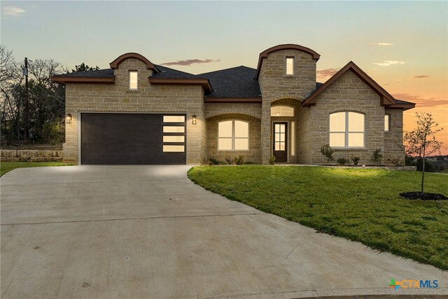 french provincial home featuring a garage and a front yard