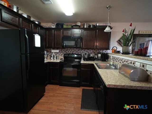 309 Bashaw Loop, Temple, TX 76502 - kitchen with black appliances, light countertops, decorative backsplash, dark brown cabinetry, and light wood-style floors