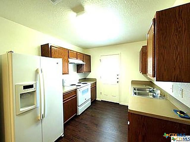 kitchen with a textured ceiling, dark hardwood / wood-style flooring, white appliances, and sink