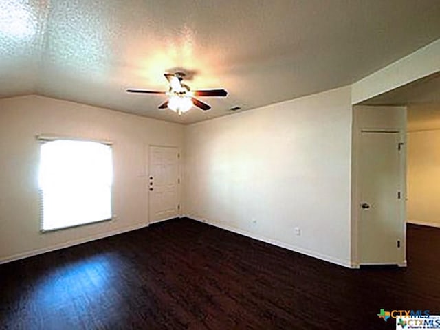 spare room featuring a textured ceiling, dark hardwood / wood-style floors, vaulted ceiling, and ceiling fan