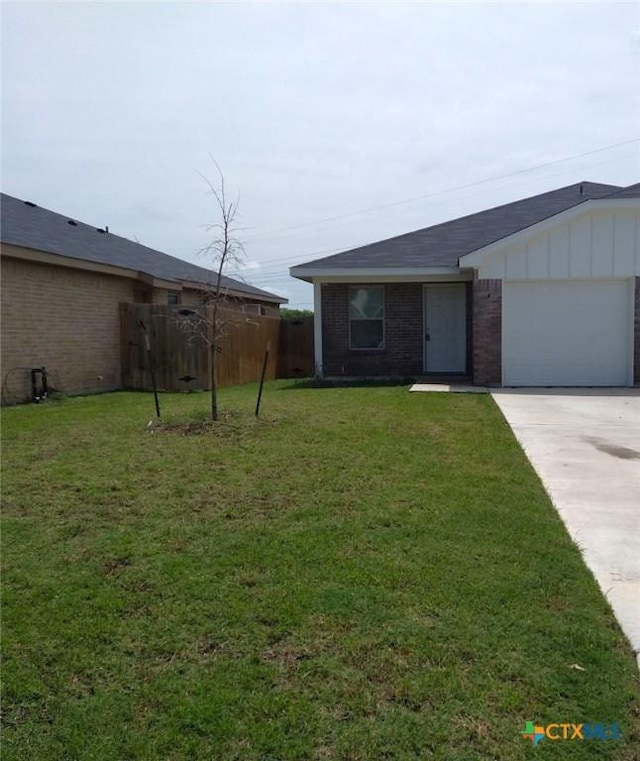 view of front of home with fence, concrete driveway, a front yard, a garage, and brick siding