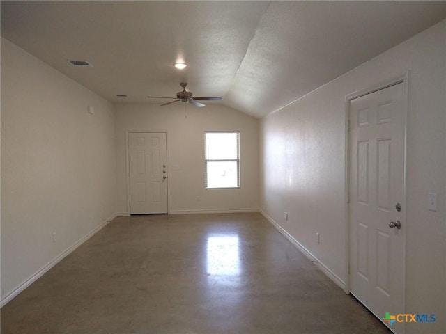 spare room with a ceiling fan, finished concrete flooring, visible vents, baseboards, and lofted ceiling