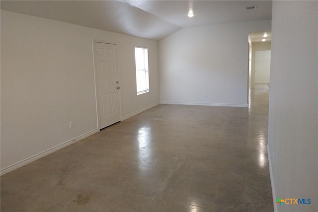 empty room featuring lofted ceiling, visible vents, baseboards, and concrete floors