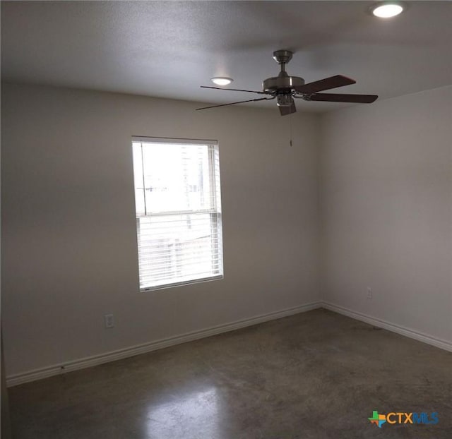 unfurnished room with ceiling fan, baseboards, and finished concrete floors