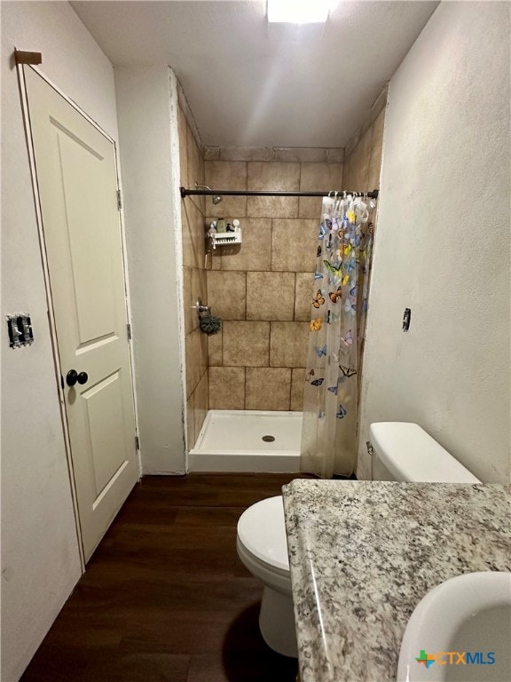 bathroom featuring curtained shower, hardwood / wood-style flooring, and toilet