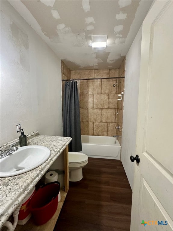 full bathroom with hardwood / wood-style floors, shower / bath combo with shower curtain, toilet, and sink