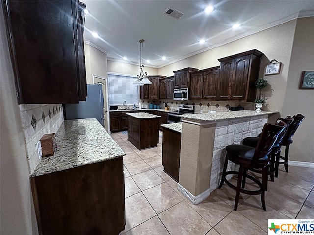 kitchen featuring stainless steel appliances, a breakfast bar, kitchen peninsula, ornamental molding, and a center island