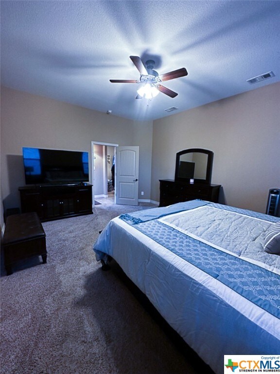 bedroom featuring a textured ceiling, ceiling fan, and carpet floors