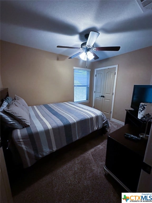 bedroom featuring ceiling fan, dark colored carpet, and a closet