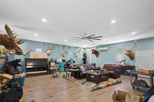 living room with a wall mounted air conditioner, recessed lighting, wood finished floors, and a ceiling fan