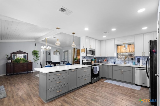 kitchen with a peninsula, gray cabinetry, visible vents, and stainless steel appliances