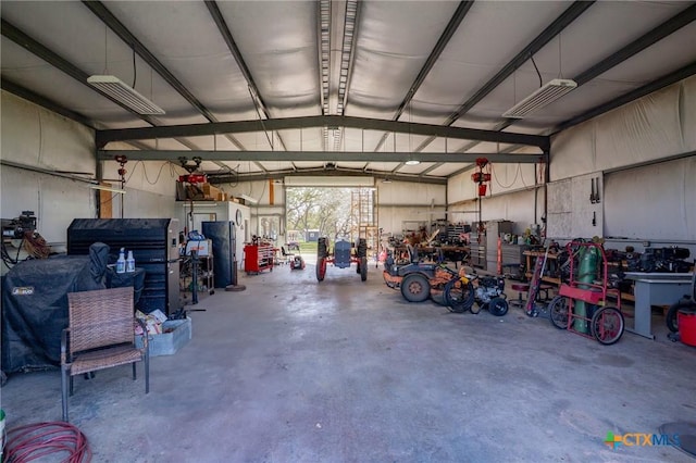 garage featuring a workshop area, visible vents, and freestanding refrigerator