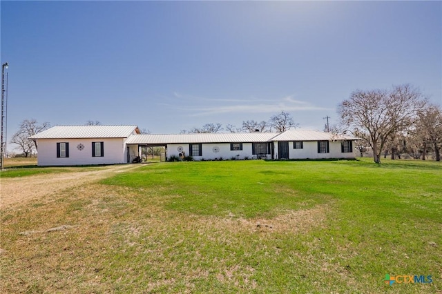 view of front facade featuring metal roof, dirt driveway, a carport, and a front lawn