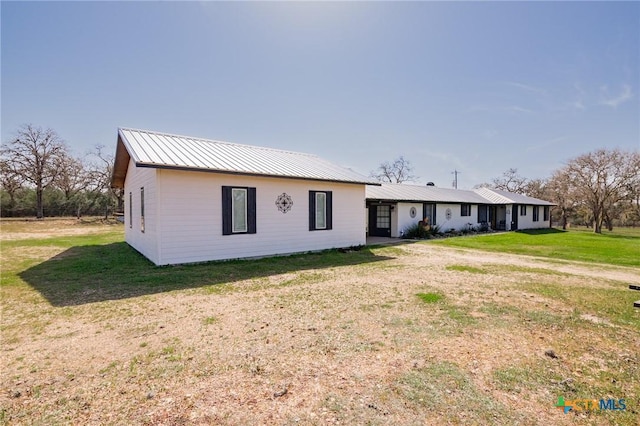 view of front of house featuring metal roof and a front yard