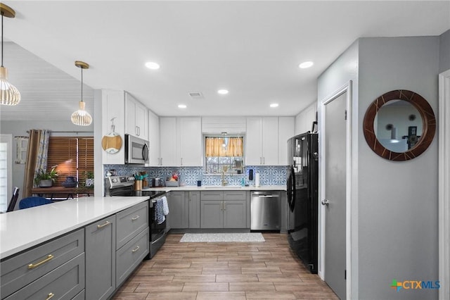 kitchen featuring tasteful backsplash, gray cabinets, appliances with stainless steel finishes, white cabinetry, and a sink