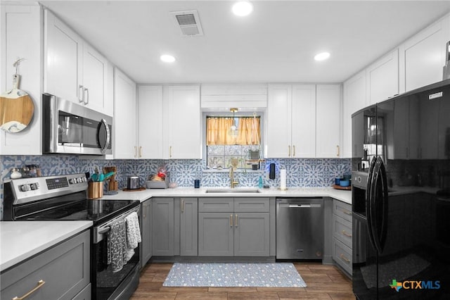 kitchen with visible vents, wood tiled floor, gray cabinets, a sink, and stainless steel appliances