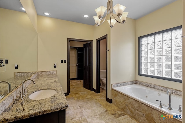 bathroom with tiled bath, vanity, a chandelier, and toilet