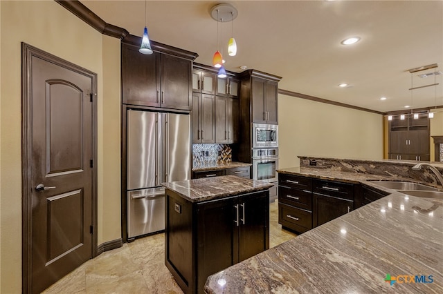 kitchen with appliances with stainless steel finishes, decorative light fixtures, sink, dark stone countertops, and a center island