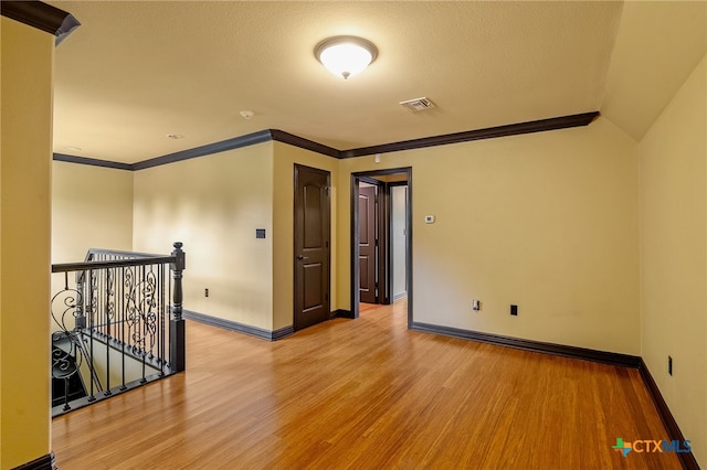 spare room with wood-type flooring, ornamental molding, and a textured ceiling