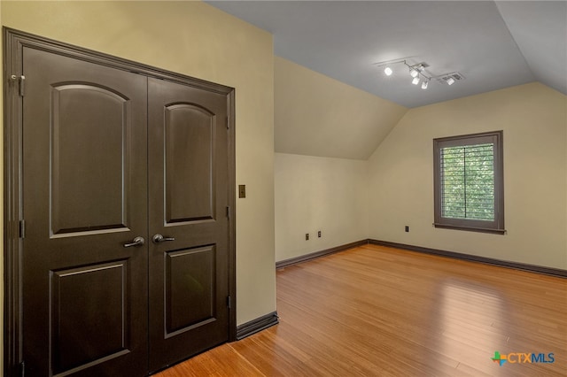 bonus room with light wood-type flooring and vaulted ceiling