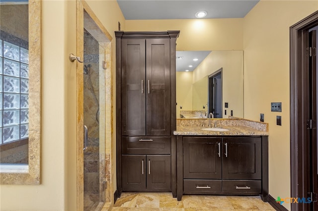 bathroom with vanity, a tile shower, and a healthy amount of sunlight