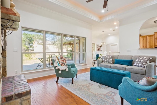 living room with a wealth of natural light, ceiling fan, hardwood / wood-style flooring, and ornamental molding