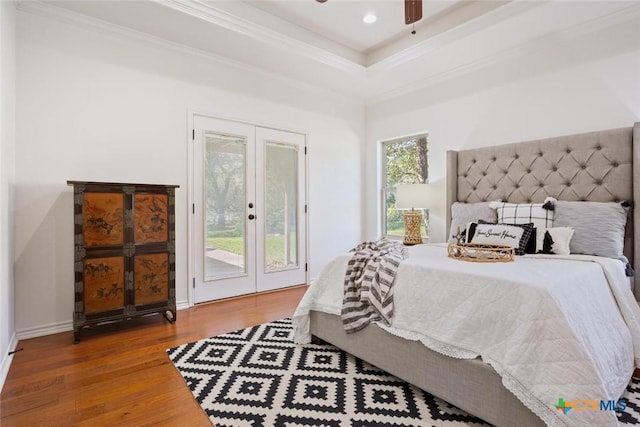 bedroom with hardwood / wood-style floors, access to outside, french doors, ceiling fan, and a tray ceiling