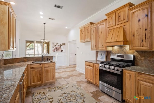 kitchen with premium range hood, sink, gas range, dark stone countertops, and decorative light fixtures