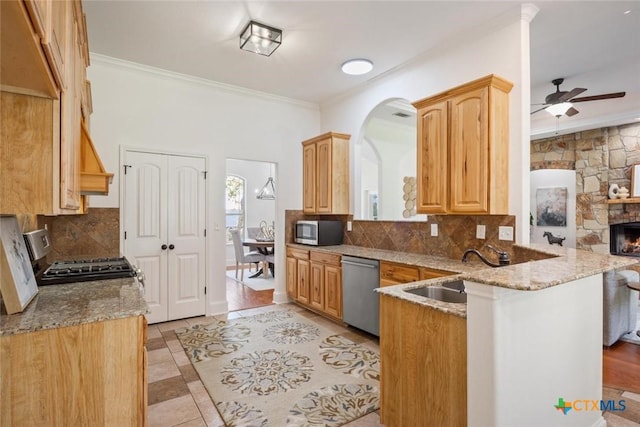 kitchen with sink, light stone countertops, tasteful backsplash, kitchen peninsula, and stainless steel appliances