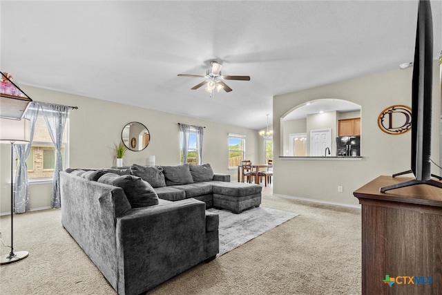 carpeted living room with ceiling fan with notable chandelier and a healthy amount of sunlight