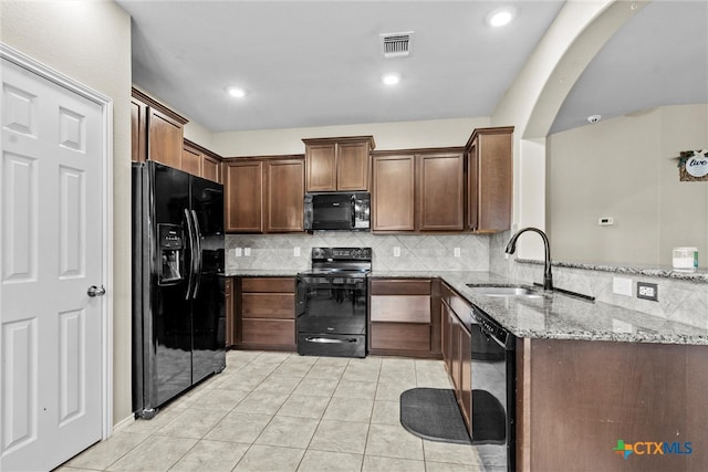 kitchen with black appliances, light tile patterned floors, sink, tasteful backsplash, and light stone countertops