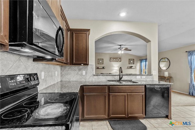 kitchen featuring black appliances, light stone counters, vaulted ceiling, and light tile patterned floors