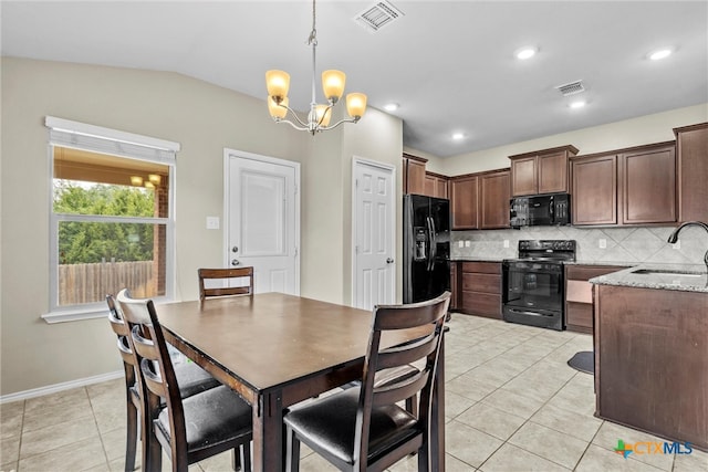 tiled dining space featuring a notable chandelier, sink, and lofted ceiling