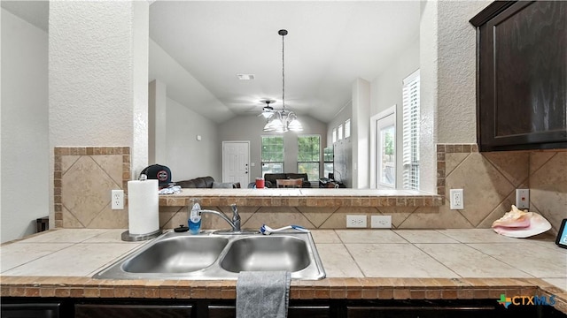 557/561 Creekside Cir, New Braunfels, TX 78130 - kitchen featuring tile countertops, vaulted ceiling, dark brown cabinetry, a textured wall, and open floor plan