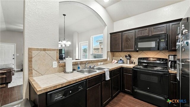 557/561 Creekside Cir, New Braunfels, TX 78130 - kitchen featuring black appliances, dark wood-style flooring, tasteful backsplash, lofted ceiling, and arched walkways