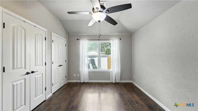 543 Scenic Terrace Dr, Canyon Lake, TX 78133 - unfurnished bedroom with multiple closets, dark wood-style flooring, vaulted ceiling, a textured wall, and a ceiling fan
