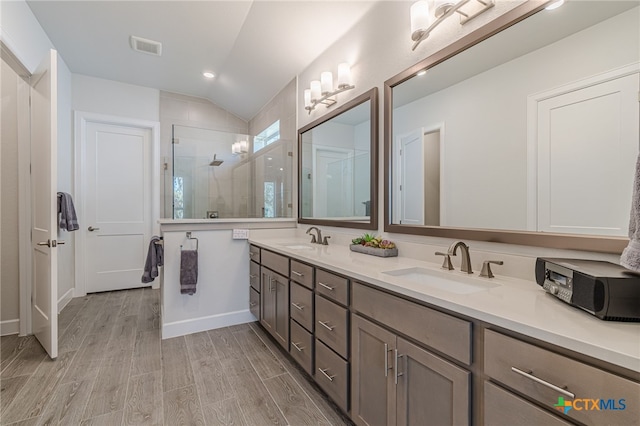 bathroom featuring vanity, hardwood / wood-style floors, a shower with shower door, and vaulted ceiling