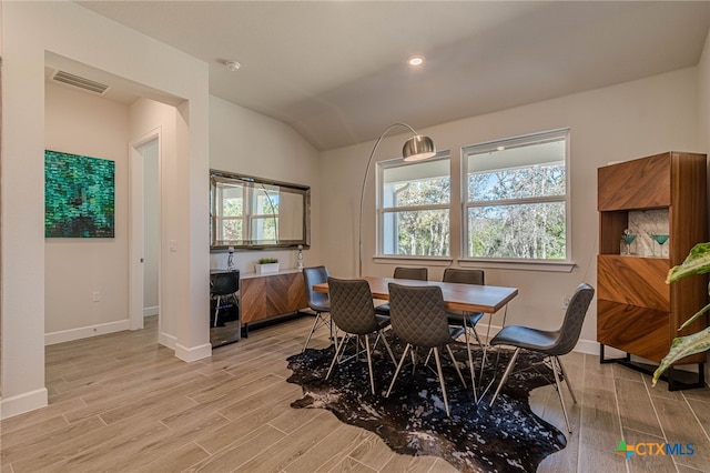 dining room with lofted ceiling and light hardwood / wood-style floors