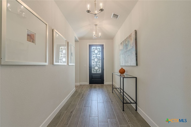 entrance foyer with dark hardwood / wood-style flooring and a notable chandelier