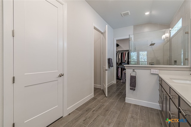 bathroom with vaulted ceiling, a wealth of natural light, vanity, and walk in shower