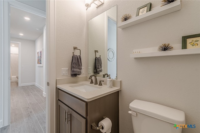 bathroom featuring vanity, hardwood / wood-style flooring, and toilet