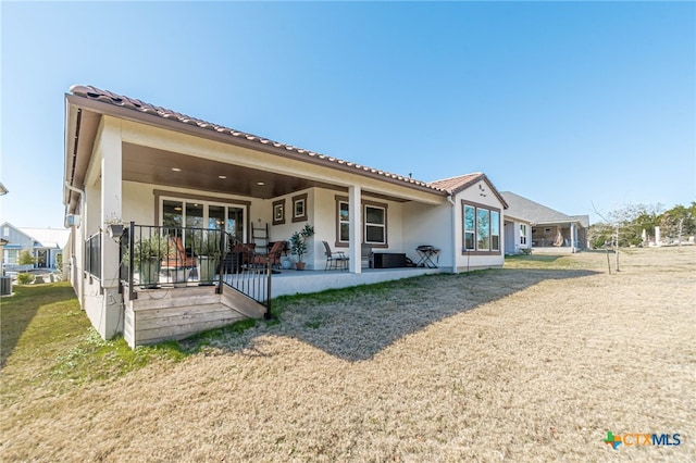 rear view of property with a yard, cooling unit, and a patio area