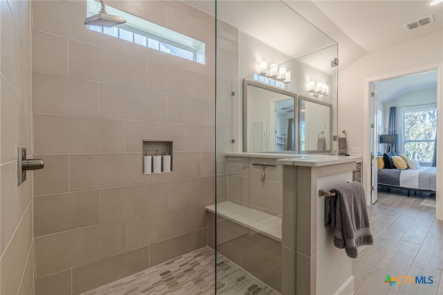 bathroom with tiled shower, wood-type flooring, and vanity