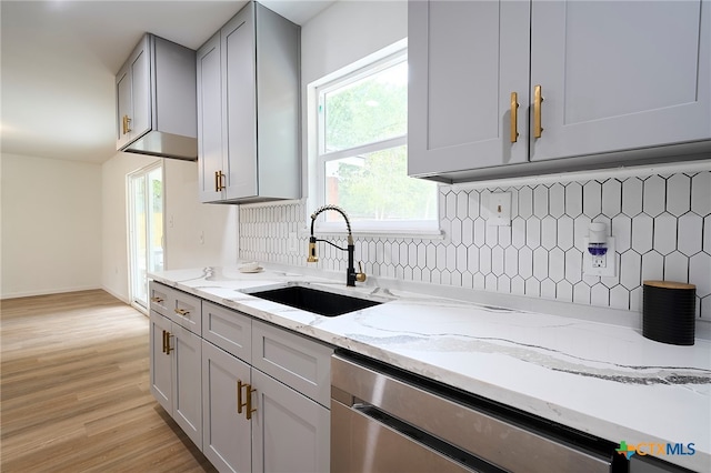 kitchen featuring sink, dishwasher, gray cabinetry, tasteful backsplash, and light stone countertops