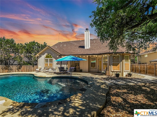 pool at dusk featuring a patio