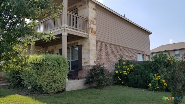 view of side of property with a yard and a balcony